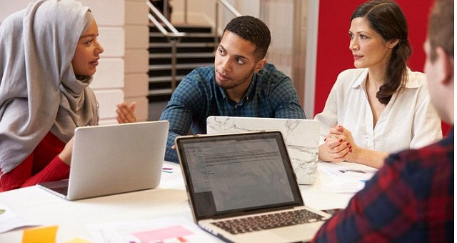 Four students discuss a topic around a table