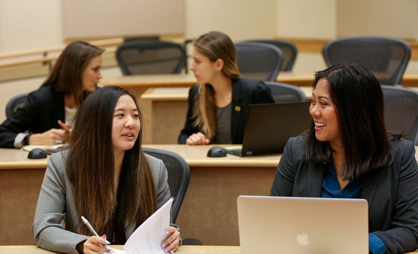 Four students at tables speaking together