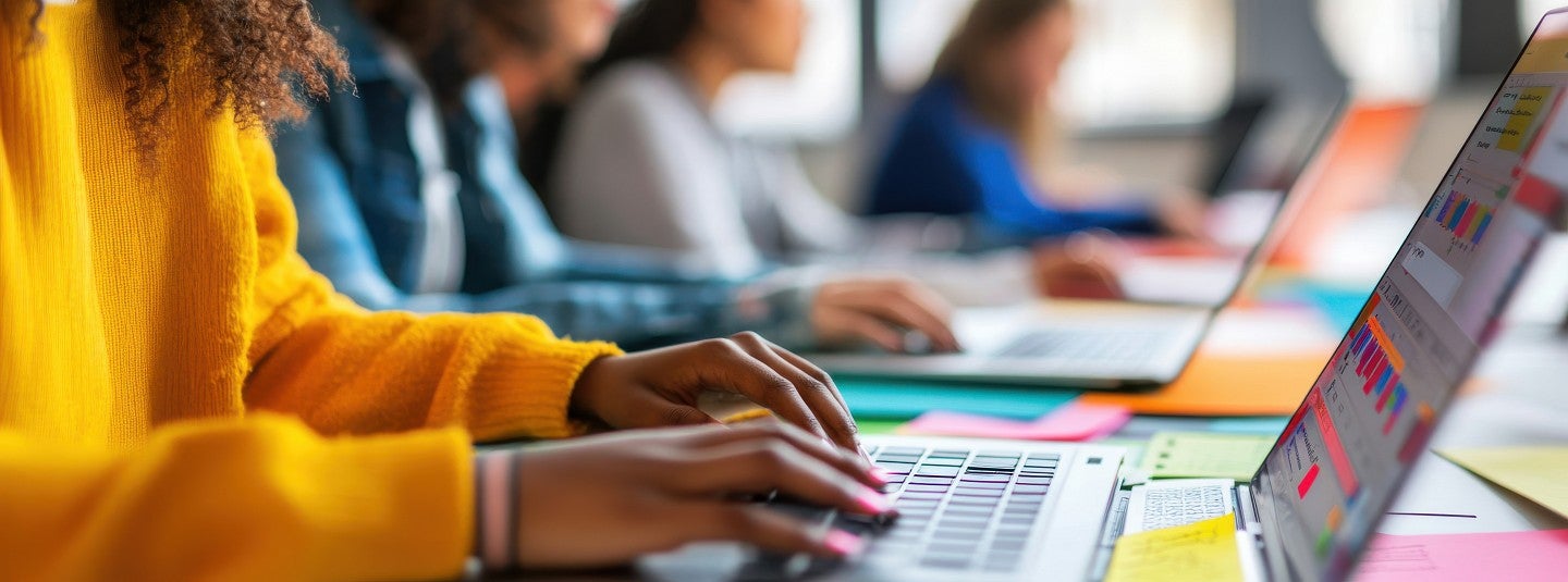 Close-up of young people working together on laptop computers
