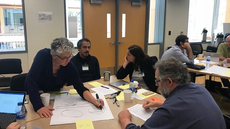 People sitting at two tables, talking and writing together.