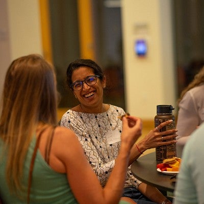 Faculty sitting at a small table talking and laughing together