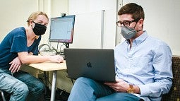 Two people discussing content on laptop