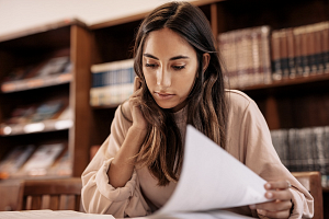 Woman looking at research paper in a library