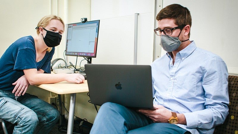 Two people discussing content on laptop